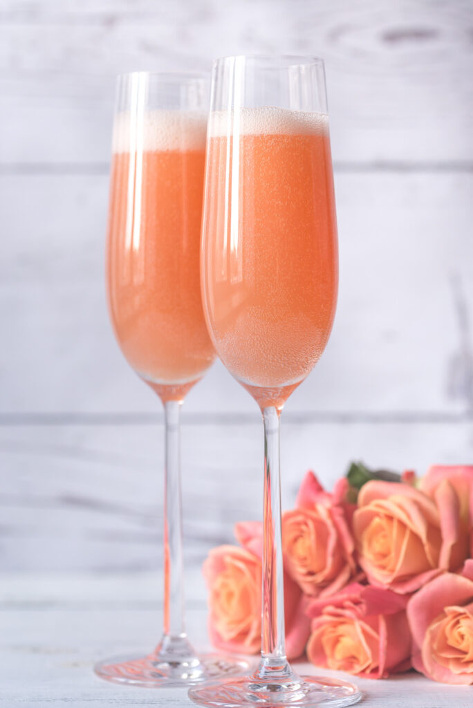 Bicchieri di Peac Bellini con sfondo di rose